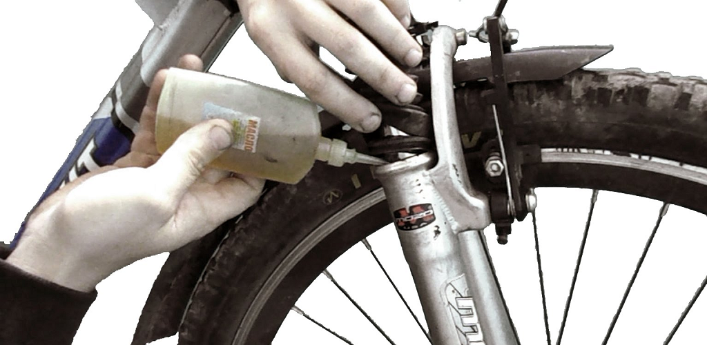 На фото – процесс смазки амортизатора велосипеда